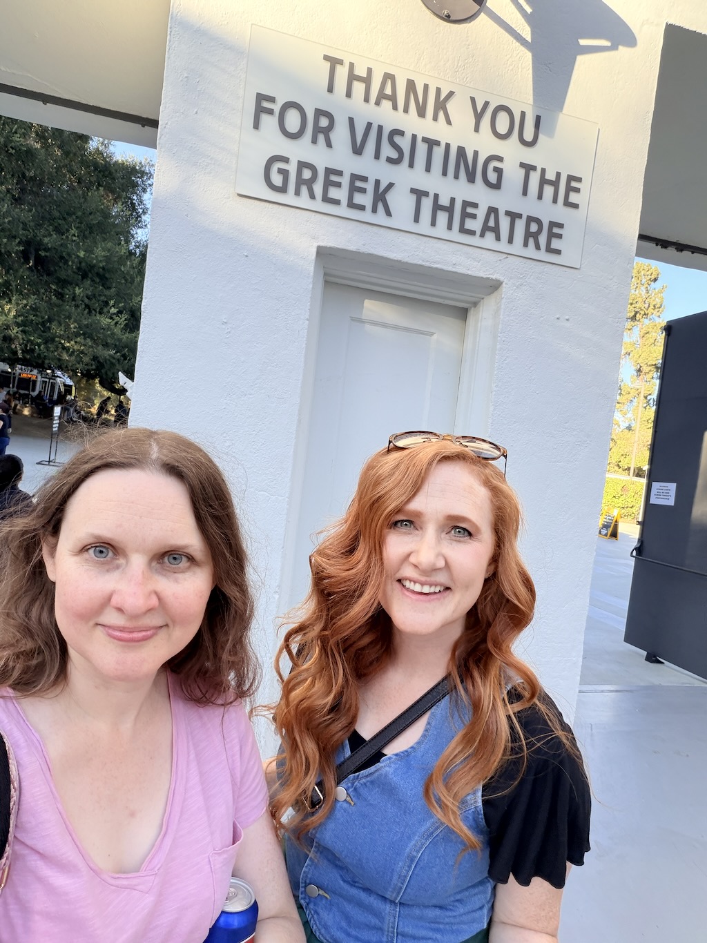 Shannon and her sister in front of a sign that says Thank You for Visiting the Greek Theatre